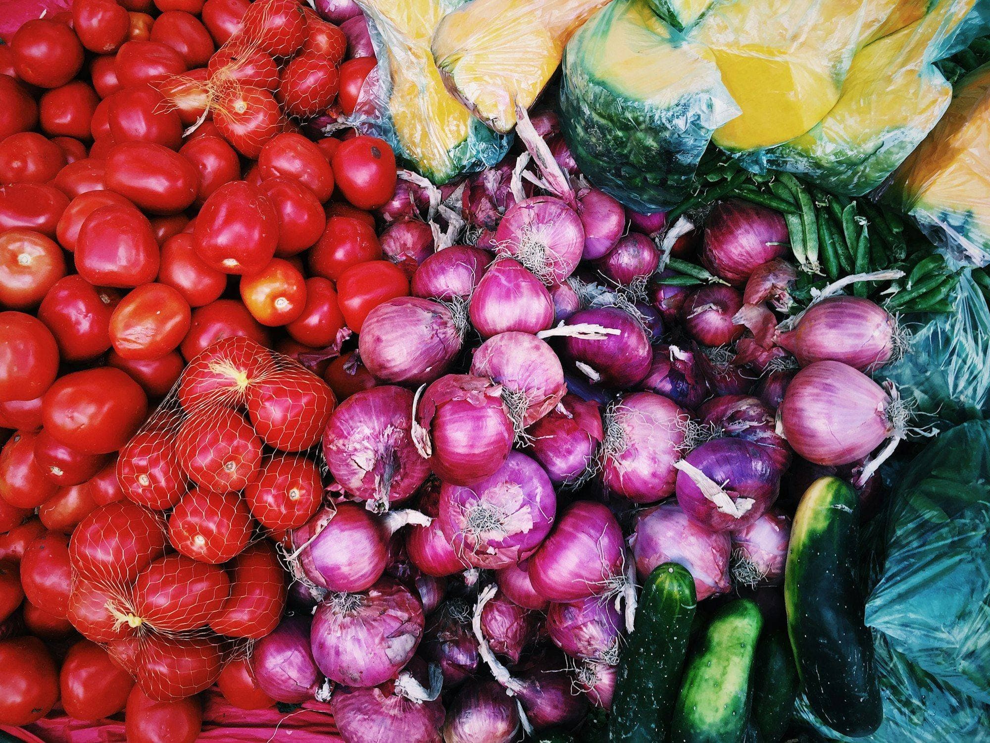 Tomatoes, red onions, cucumbers and greens photographed from above